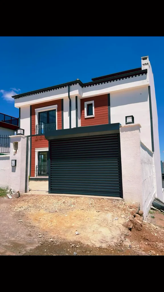 Villa girişindeki antrasit otomatik garaj kepengini gösteren sessiz saha videosu