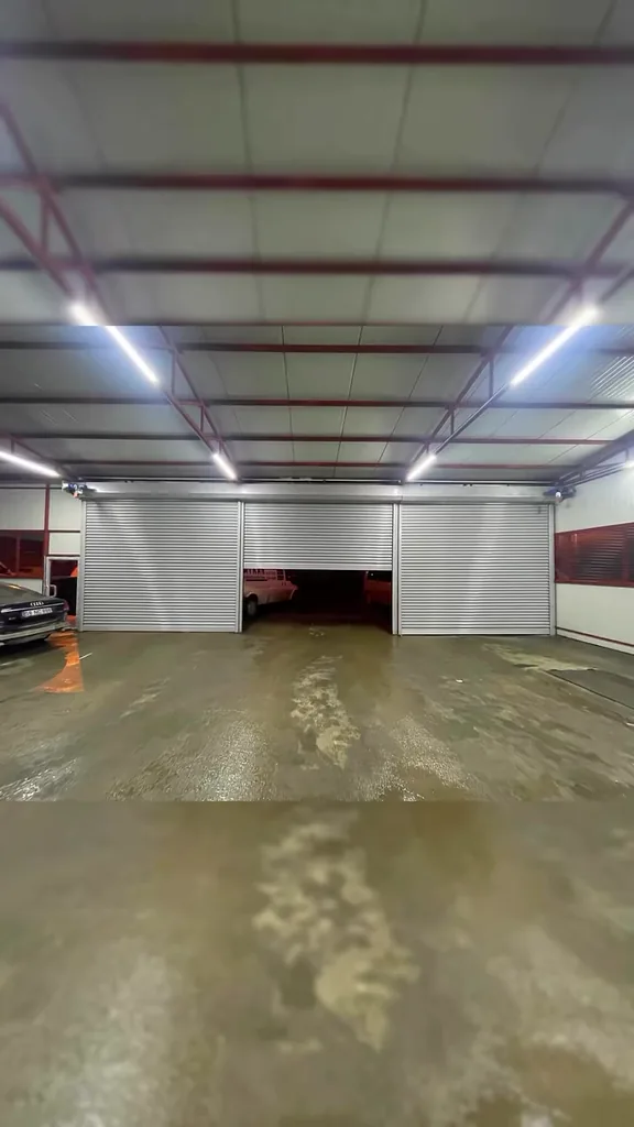 Kapalı otoparkta çalışan üç otomatik kepenk sistemini gösteren sessiz saha videosu