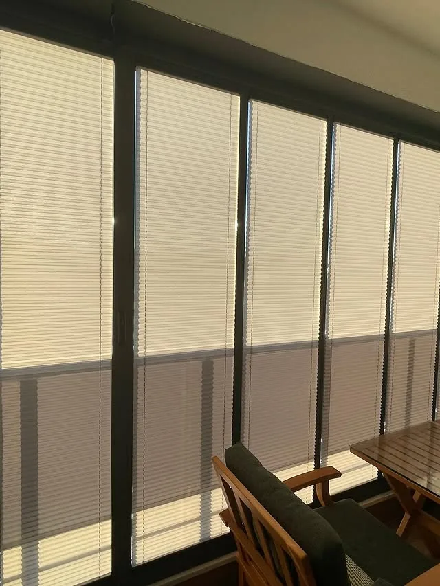 Balkon camlarına uygulanmış açık renk plise perde sistemi